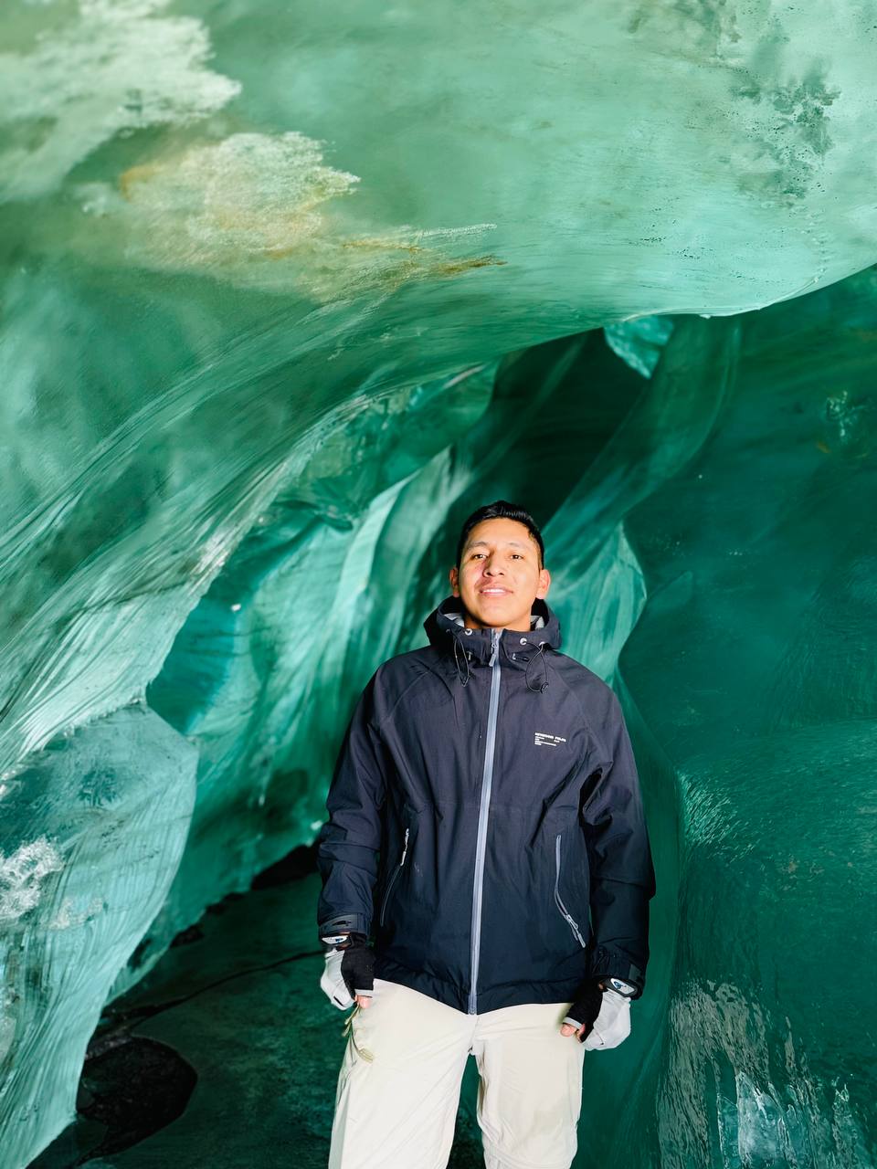 Guía de turismo de aureaperuexperience sonriente dentro de una cueva de hielo turquesa en los Andes