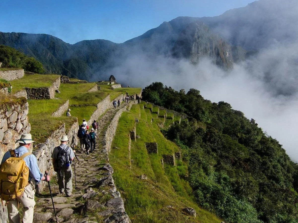 Sendero empedrado del Camino Inca entre terrazas y montañas cubiertas de niebla